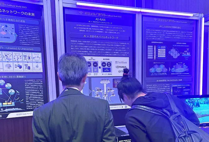 次世代のモバイルネットワーク技術「AI-RAN」の展示を覗き込む落合氏